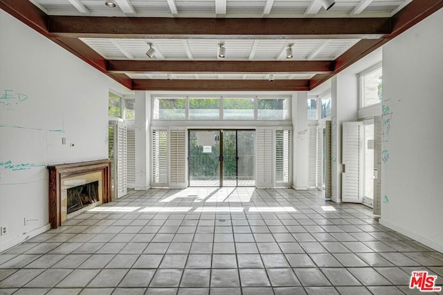 unfurnished living room featuring a high ceiling, rail lighting, and beamed ceiling