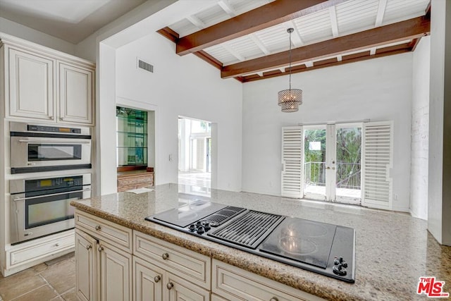 kitchen featuring cream cabinetry, black electric cooktop, hanging light fixtures, double oven, and beamed ceiling