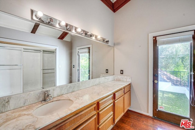 bathroom with plenty of natural light, beam ceiling, hardwood / wood-style floors, and vanity