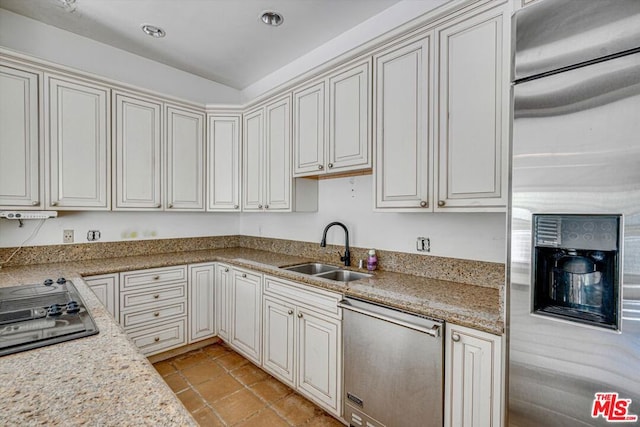 kitchen with light stone countertops, appliances with stainless steel finishes, and sink