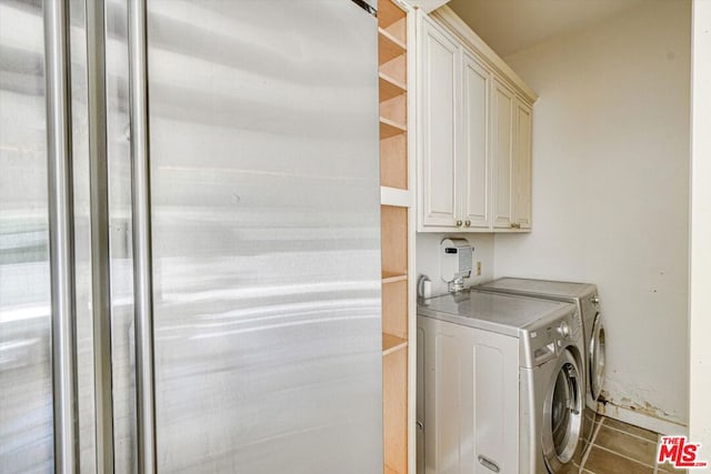 clothes washing area with tile patterned flooring, washing machine and dryer, and cabinets