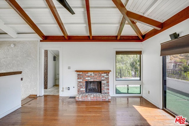 unfurnished living room featuring lofted ceiling with beams, a fireplace, and hardwood / wood-style floors