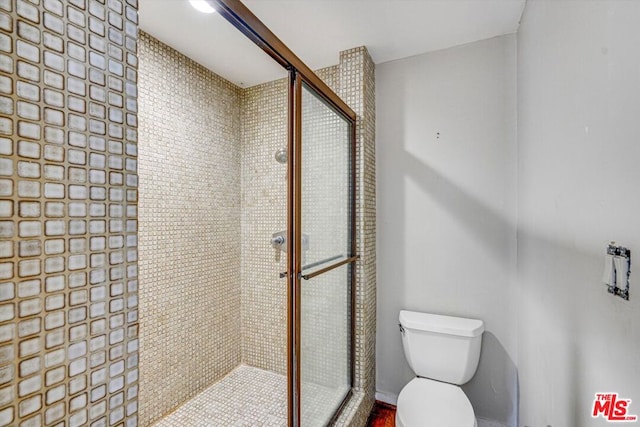 bathroom featuring toilet and a shower with shower door