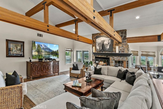 living room with a stone fireplace, plenty of natural light, hardwood / wood-style flooring, high vaulted ceiling, and beam ceiling