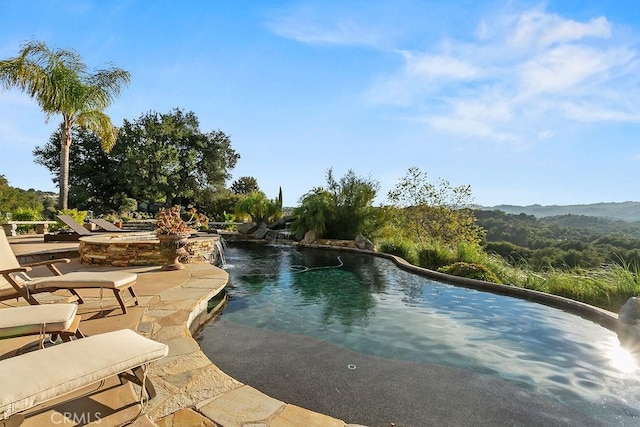 view of swimming pool with a water and mountain view, an in ground hot tub, and a patio