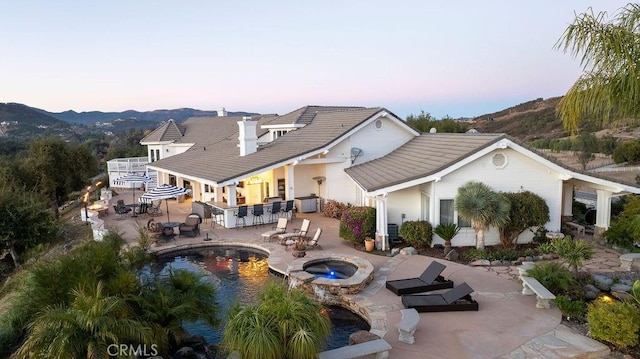 exterior space with an in ground hot tub, a mountain view, central AC unit, an outdoor bar, and a patio