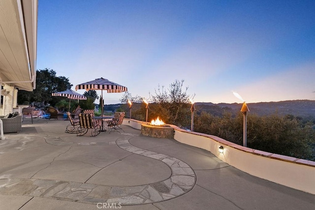 patio terrace at dusk featuring a mountain view and a fire pit