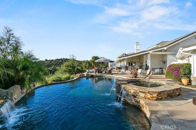 view of pool with an in ground hot tub, a patio area, and pool water feature