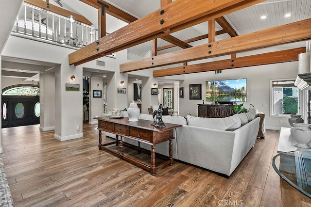 living room featuring high vaulted ceiling, wood-type flooring, and beamed ceiling