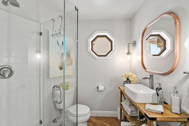 bathroom with toilet, a shower with shower door, hardwood / wood-style flooring, and sink