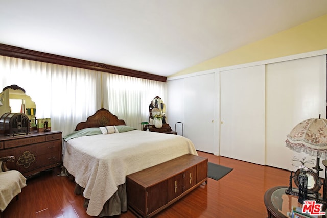 bedroom with hardwood / wood-style flooring, two closets, and lofted ceiling