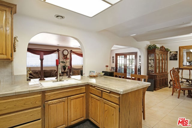 kitchen with a healthy amount of sunlight, kitchen peninsula, sink, and tile countertops