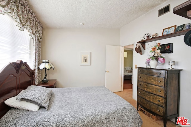 bedroom with a textured ceiling and light carpet