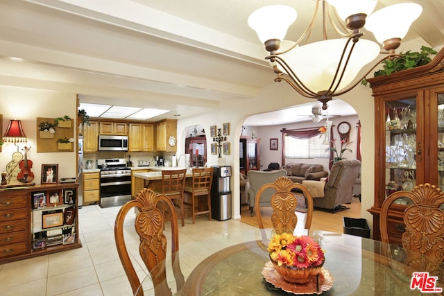 tiled dining area featuring beam ceiling, ceiling fan with notable chandelier, and sink