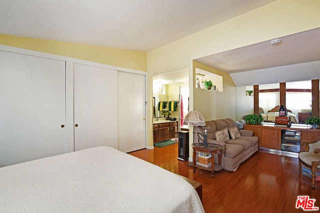 bedroom featuring multiple closets, vaulted ceiling, connected bathroom, and hardwood / wood-style floors