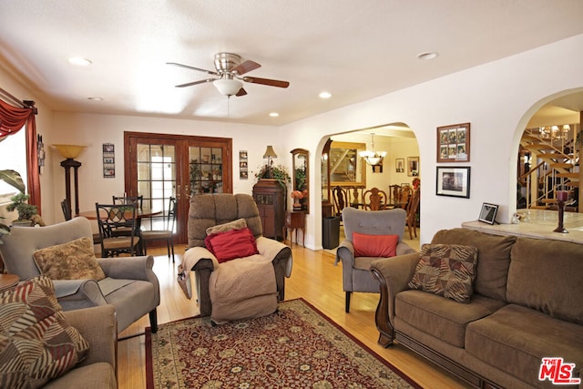 living room featuring ceiling fan with notable chandelier and light hardwood / wood-style floors