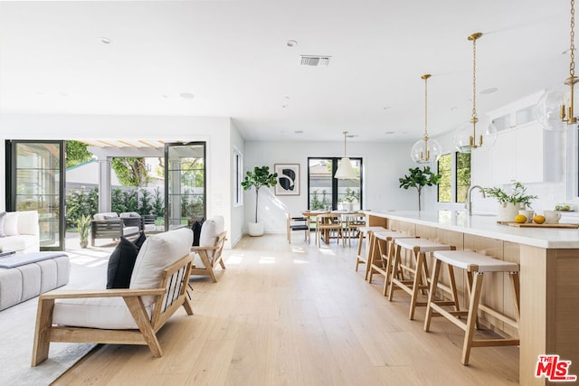 living room with sink, a notable chandelier, a wealth of natural light, and light hardwood / wood-style floors