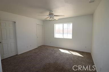 unfurnished room featuring ceiling fan and dark carpet