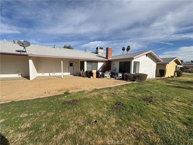 back of house with a yard and a patio