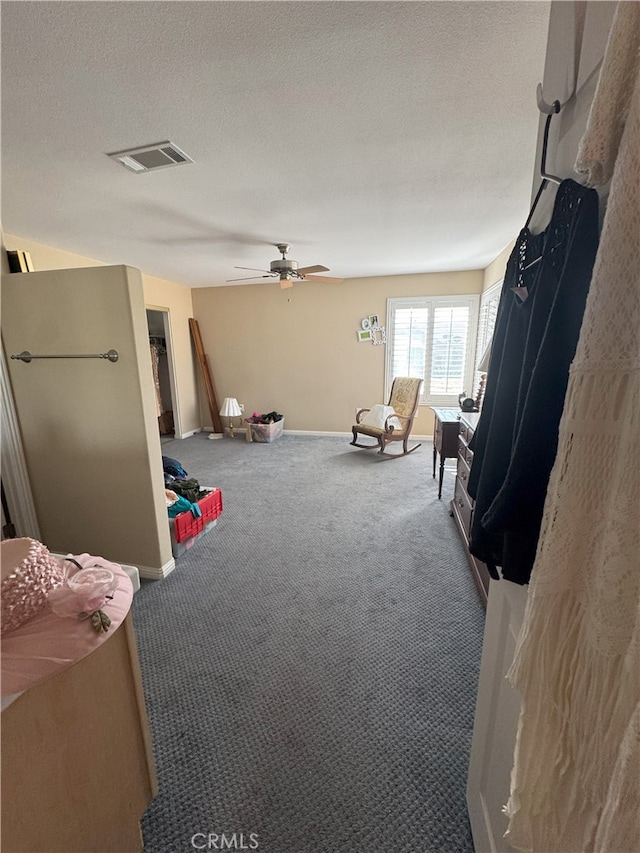 interior space featuring a textured ceiling, ceiling fan, and carpet flooring