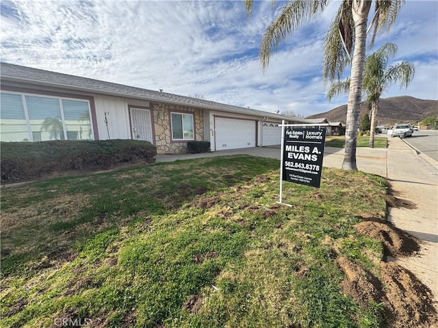 view of front of house with a garage, a front lawn, and a mountain view