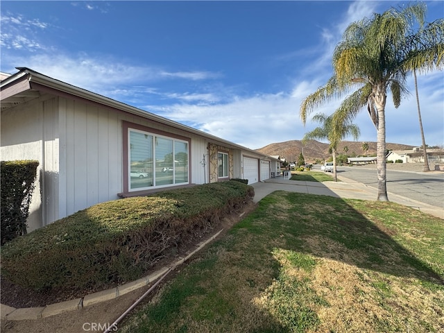 view of side of home featuring a garage and a lawn