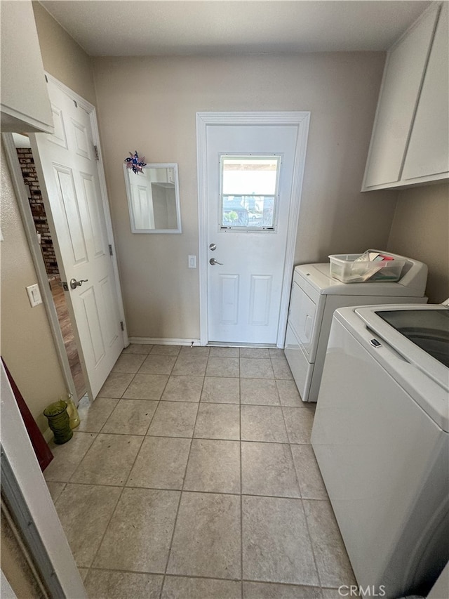 washroom with light tile patterned floors, washer and dryer, and cabinets