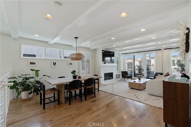 dining room featuring beam ceiling and light hardwood / wood-style flooring