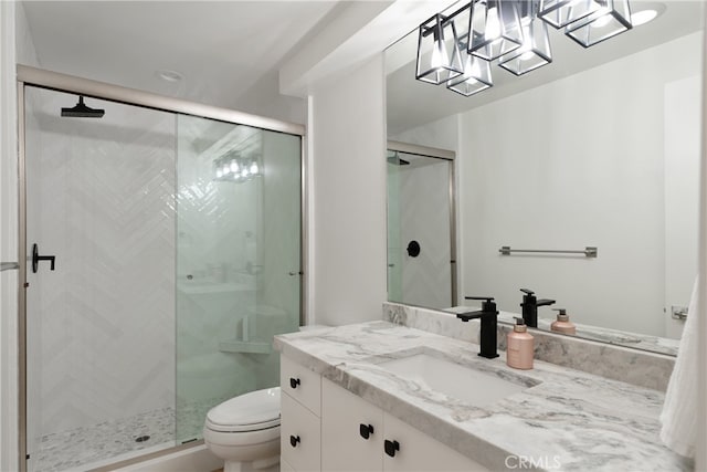 bathroom featuring toilet, vanity, and a shower with shower door