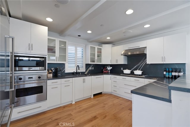 kitchen featuring white cabinets, backsplash, appliances with stainless steel finishes, and beam ceiling