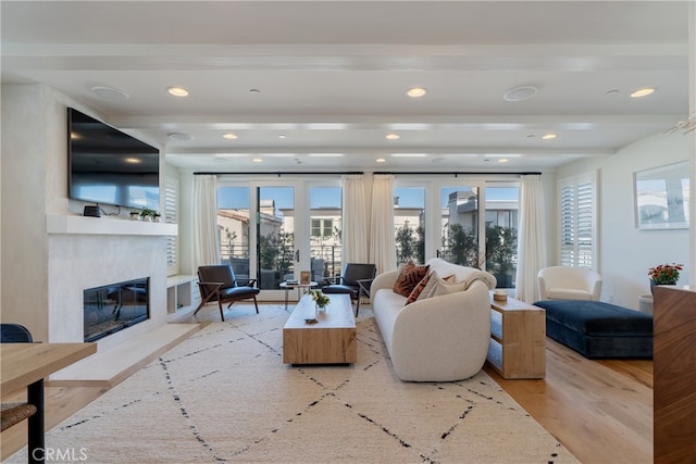 living room with beam ceiling, a fireplace, and light hardwood / wood-style flooring