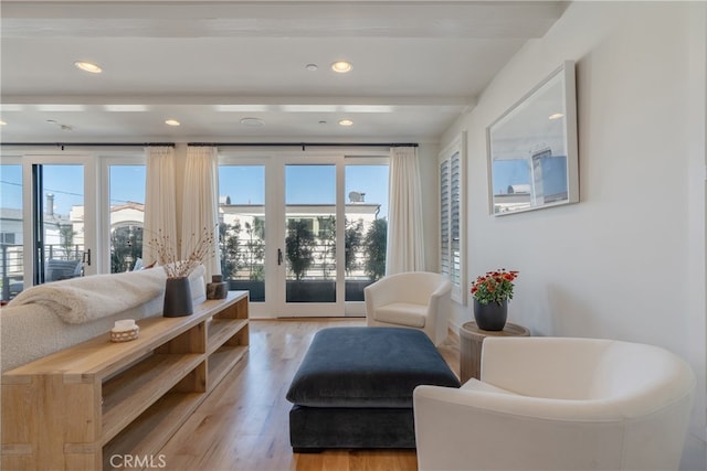 living area featuring beam ceiling, french doors, and light hardwood / wood-style flooring