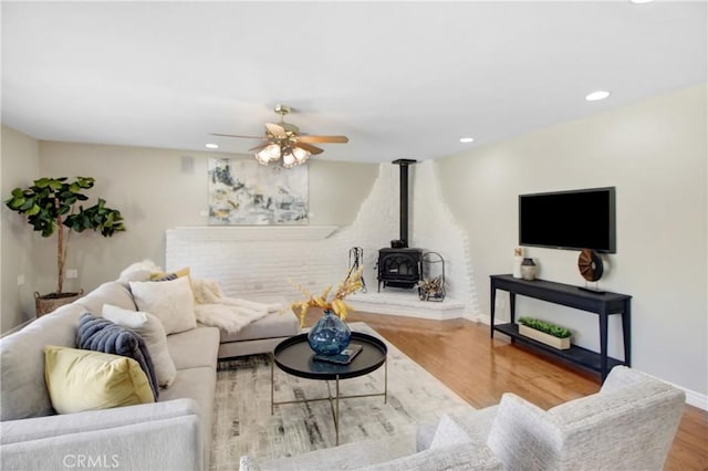 living room with hardwood / wood-style flooring, a wood stove, and ceiling fan