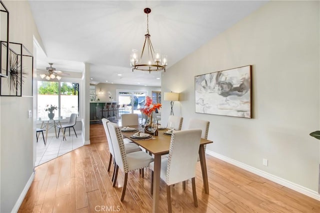 dining room with ceiling fan with notable chandelier and light wood-type flooring