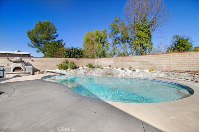 view of pool featuring a patio and an outdoor stone fireplace