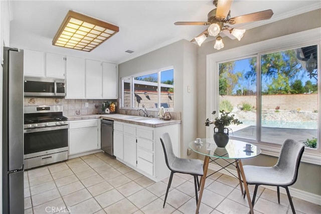 kitchen with tasteful backsplash, sink, light tile patterned flooring, white cabinetry, and stainless steel appliances