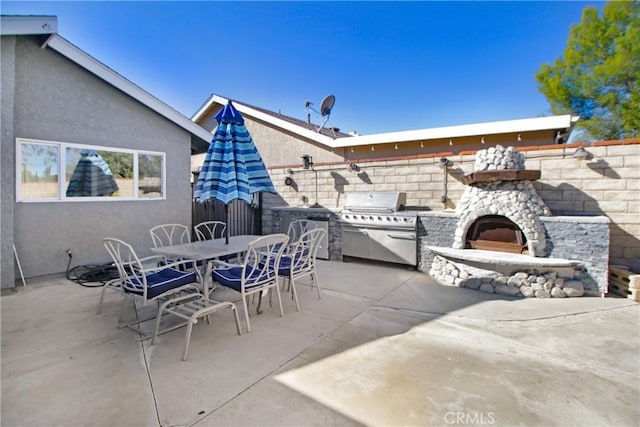 view of patio / terrace featuring a grill, an outdoor stone fireplace, and area for grilling