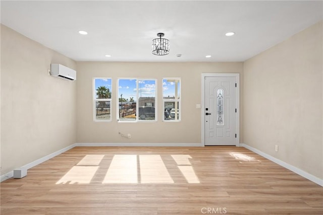 foyer entrance featuring an AC wall unit, a chandelier, and light hardwood / wood-style flooring