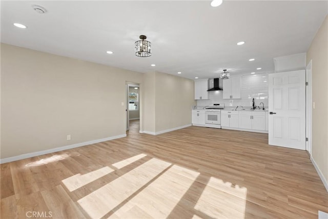 unfurnished living room featuring sink, light hardwood / wood-style flooring, and a chandelier