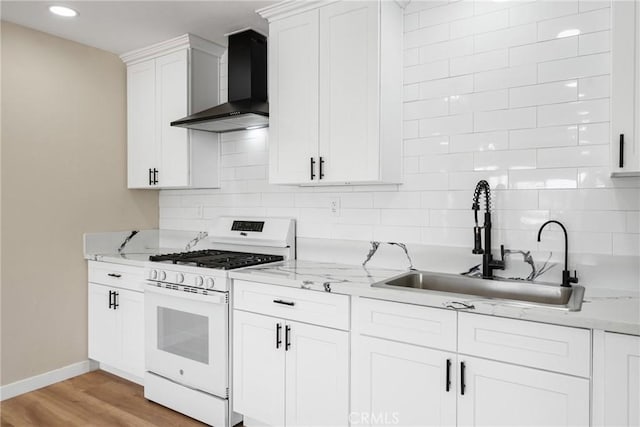 kitchen with sink, light hardwood / wood-style flooring, white gas range, white cabinets, and wall chimney exhaust hood