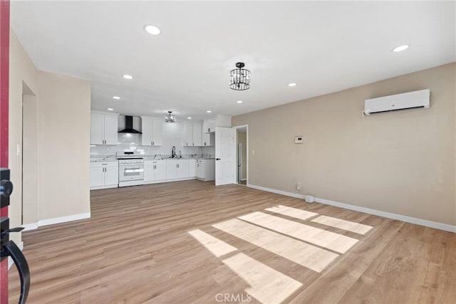 unfurnished living room with sink, light hardwood / wood-style flooring, a wall mounted AC, and an inviting chandelier