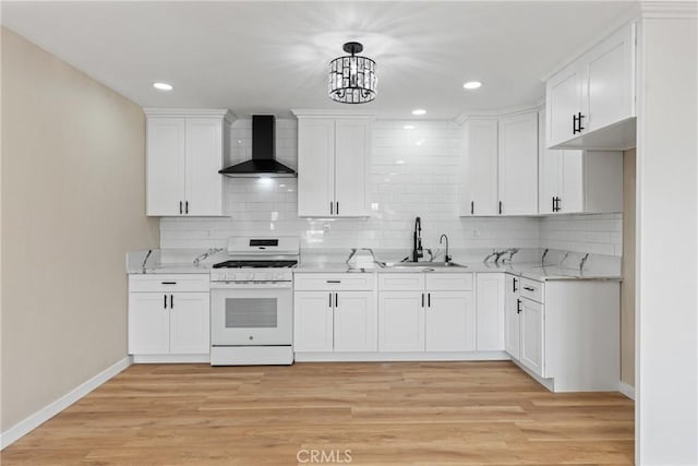 kitchen with white cabinetry, light hardwood / wood-style floors, wall chimney range hood, white gas range, and sink