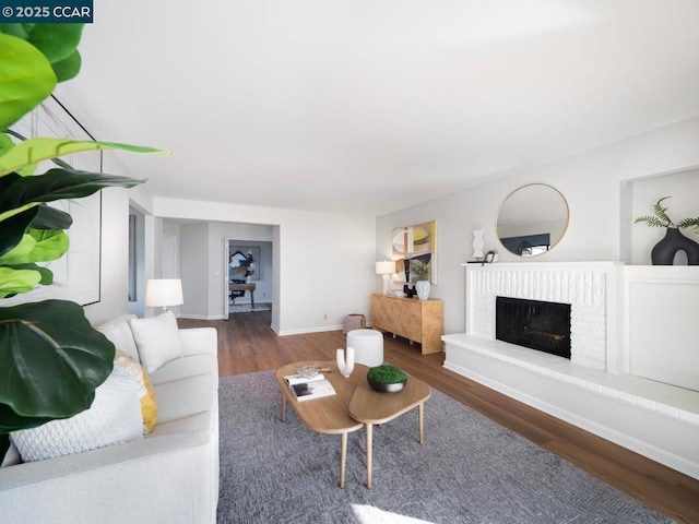 living room with a brick fireplace and hardwood / wood-style flooring