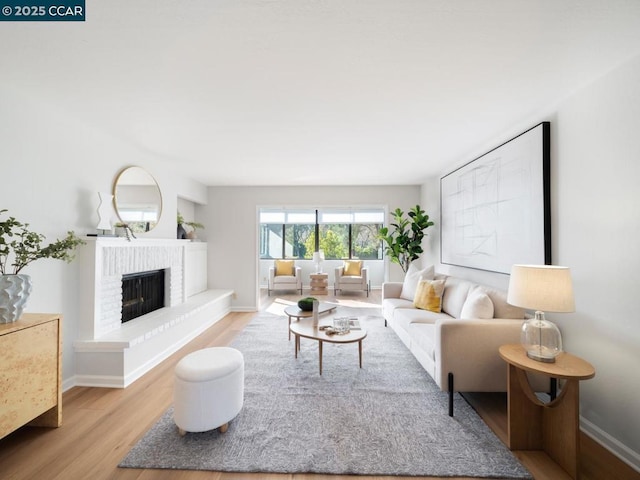 living room with a brick fireplace and light hardwood / wood-style floors