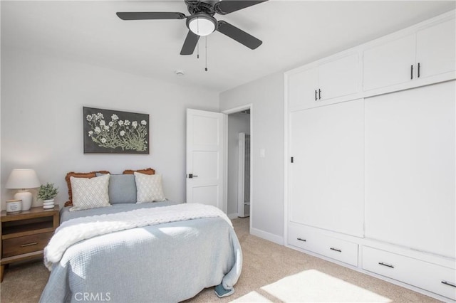 bedroom with ceiling fan, light colored carpet, and a closet