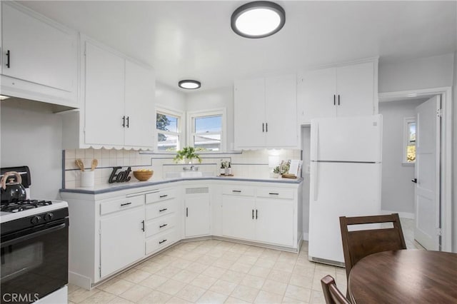 kitchen featuring white cabinets, backsplash, range with gas cooktop, and white refrigerator