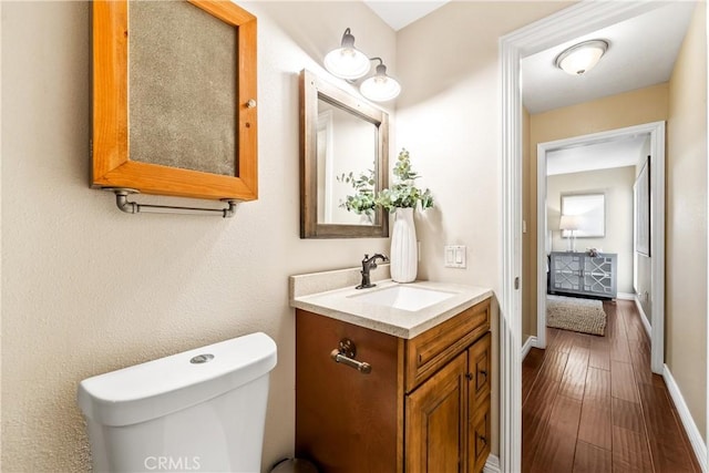 bathroom with hardwood / wood-style flooring, toilet, and vanity