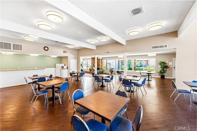 dining space with dark wood-type flooring and beamed ceiling