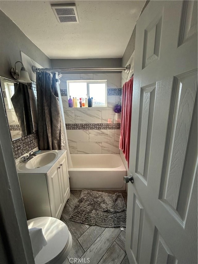 full bathroom featuring a textured ceiling, toilet, vanity, and shower / bath combination with curtain