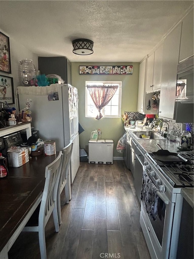 kitchen with a textured ceiling, white cabinets, gas range gas stove, dark hardwood / wood-style flooring, and sink